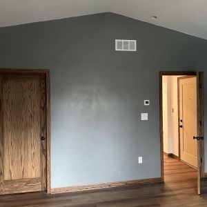 Interior view of a vaulted ceiling bedroom addition with luxury vinyl plank flooring and neutral gray paint.
