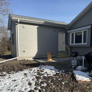 Exterior view of a seamless sunroom-to-bedroom conversion showing matched siding and professional roof integration.
