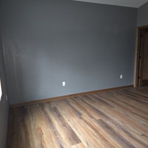 Spacious new bedroom interior featuring natural light, wood-tone flooring, and modern trim work in a home addition.