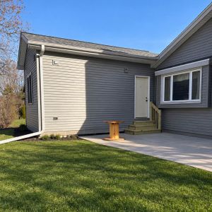 Exterior view of a seamless sunroom-to-bedroom conversion showing matched siding and professional roof integration.