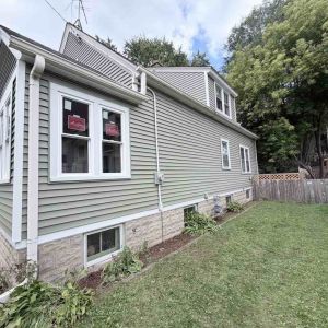 After view of renovated home side exterior featuring fresh green siding and new white window trim.   
